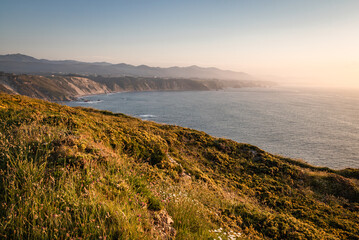 hiking on steep cliffs above atlantic ocean, with a scenic views in sunset, asturias, spain