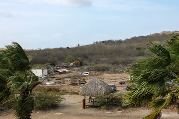 Out of sight of tourists, vacant land with lots of trash, old car parts, and palm trees
