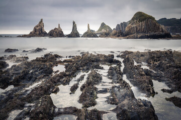 scenic seascape with rising rocks on the beach in long exposure