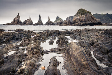 scenic seascape with rising rocks on the beach in long exposure