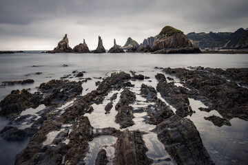 scenic seascape with rising rocks on the beach in long exposure