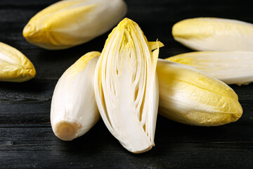 Raw chicory or endives salad roots on wooden background