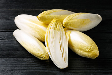 Raw chicory or endives salad roots on wooden background