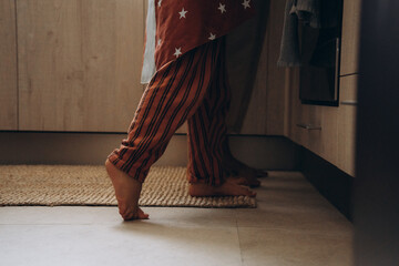 Cozy morning at home. A barefoot child in striped pajamas plays and spends time in a warm, inviting interior with natural light and a relaxed atmosphere.
