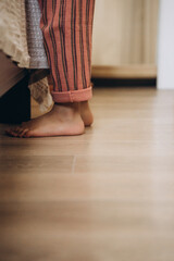 Cozy morning at home. A barefoot child in striped pajamas plays and spends time in a warm, inviting interior with natural light and a relaxed atmosphere.