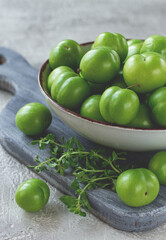 Tkemali, green cherry plum, in a bowl, on a gray table, top view, natural light, no people,