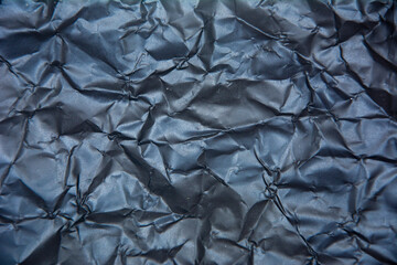 Black background with heavy wrinkles. Recycled black kraft paper texture as background.