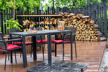 Table and chairs on the summer terrace of a cafe after the rain. Spices on the table.