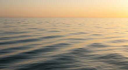 Calm ocean surface reflecting the warm light of the setting sun over the water