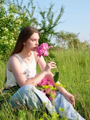 Happy smiling woman outdoors with pink peony flowers enjoying life in the moment at sunset
