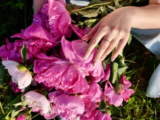 Happy smiling woman outdoors with pink peony flowers enjoying life in the moment at sunset