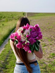 Happy smiling woman outdoors with pink peony flowers enjoying life in the moment at sunset