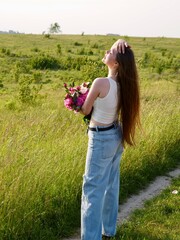 Happy smiling woman outdoors with pink peony flowers enjoying life in the moment at sunset