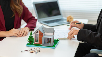 Real estate agent is in the office with the customer to prepare the documents for the real estate sale. The customer signs the sales contract before handing over the property to the customer.