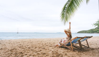 Rear view solo travel woman relaxing at the sandy beach sitting on sun bed summer holidays rest in southeast asia