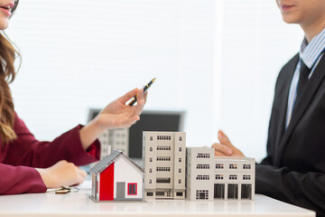 Inside a real estate office a real estate agent is presenting a condominium unit for sale to a client and offering a valuable promotion to entice the client to purchase their own property. copy space