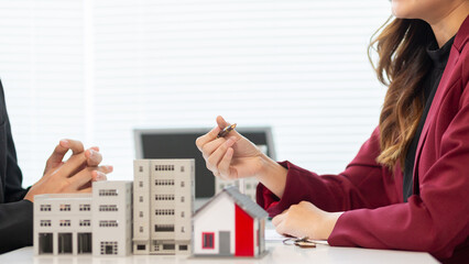 Inside a real estate office a real estate agent is presenting a condominium unit for sale to a client and offering a valuable promotion to entice the client to purchase their own property. copy space