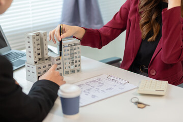 Inside a real estate office a real estate agent is presenting a condominium unit for sale to a client and offering a valuable promotion to entice the client to purchase their own property. copy space
