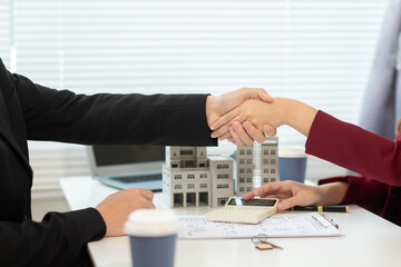 Inside a real estate office a real estate agent is presenting a condominium unit for sale to a client and offering a valuable promotion to entice the client to purchase their own property. copy space