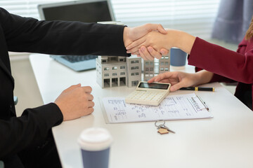Inside a real estate office a real estate agent is presenting a condominium unit for sale to a client and offering a valuable promotion to entice the client to purchase their own property. copy space