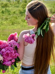 Fototapeta premium Happy smiling woman outdoors with pink peony flowers enjoying life in the moment at sunset