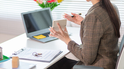 Inside a real estate office a real estate agent is using a house mockup to present the design and promotions that the client will receive when they sign sales contract. Real estate investment concept