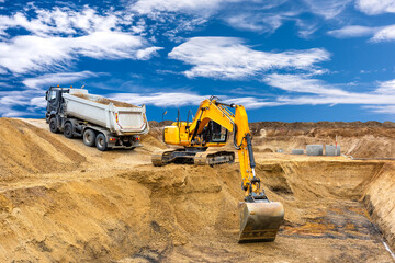 Ein Bagger arbeitet auf einer Baustelle mit Aushub für das Fundament von einem Wohnhaus -...