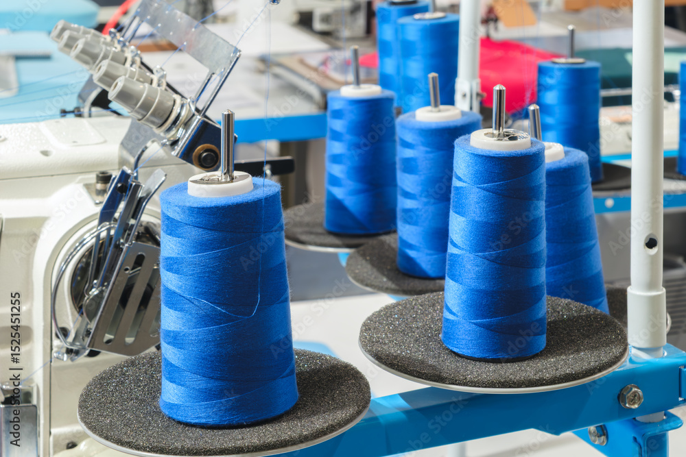 Aufkleber A group of blue and white spools of thread are being made on a machine. The spools are arranged in a row and are of varying sizes