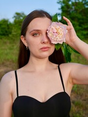 Happy smiling woman outdoors with pink peony flowers enjoying life in the moment at sunset