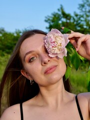 Happy smiling woman outdoors with pink peony flowers enjoying life in the moment at sunset