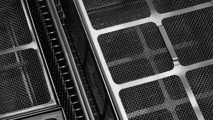 A close up of a black and silver mesh with squares. The mesh is made of metal and has a grid pattern