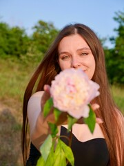 Happy smiling woman outdoors with pink peony flowers enjoying life in the moment at sunset