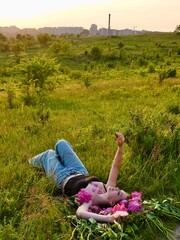 Happy smiling woman outdoors with pink peony flowers enjoying life in the moment at sunset