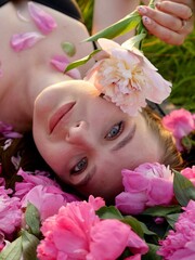 Happy smiling woman outdoors with pink peony flowers enjoying life in the moment at sunset