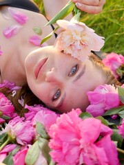 Happy smiling woman outdoors with pink peony flowers enjoying life in the moment at sunset