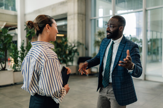 Businessman explaining strategy to female colleague in office lobby
