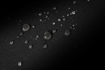 Macro photo of water droplets on black waterproof fabric, showing hydrophobic properties with a...
