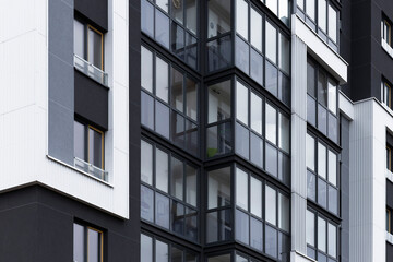 Building with modern architecture and glass balconies. Geometric high rise apartment facade with