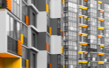 Colorful apartment building with orange, yellow, and gray facade. Blurry vertical structure in urban