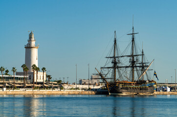 Malaga port with historic sailing ship and lighthouse, Andalusia, Spain