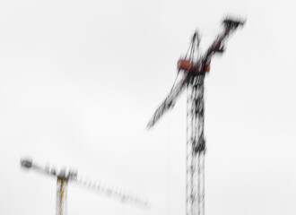 Defocused construction crane under overcast sky in monochrome frame. Atmospheric and artistic