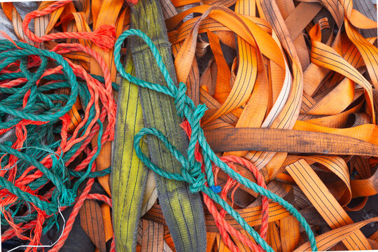 Cargo straps lie in a pile with ropes.