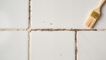 Cleaning grout lines with a brush on white tiled surface  