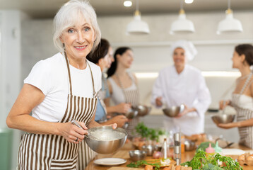 Elderly woman learns to prepare dish at cooking master class
