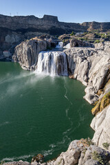 A waterfall is seen in the distance, with a body of water in the foreground