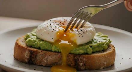 Fork piercing soft-poached egg on avocado toast