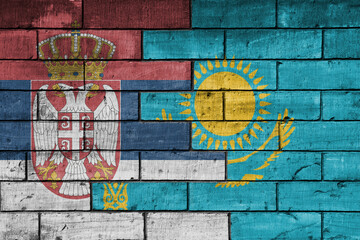 colourful painted big national flag of serbia and flag of kazakhstan on a massive old brick wall background. concept