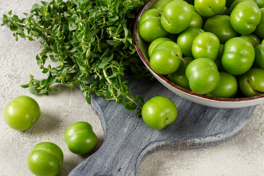Tkemali, green cherry plum, in a bowl, on a gray table, top view, natural light, no people,