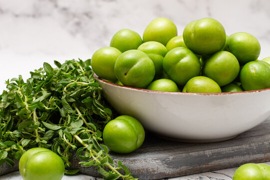 Tkemali, green cherry plum, in a bowl, on a gray table, top view, natural light, no people,