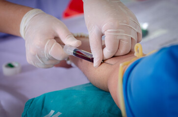 Close up nurse pricking needle syringe in the arm patient drawing blood sample for blood test , Health check